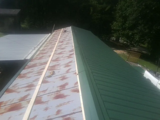 Old rusted panels beside newly installed green metal roofing — Wind Damage Roof Repair by Roofing Brothers in Joliet