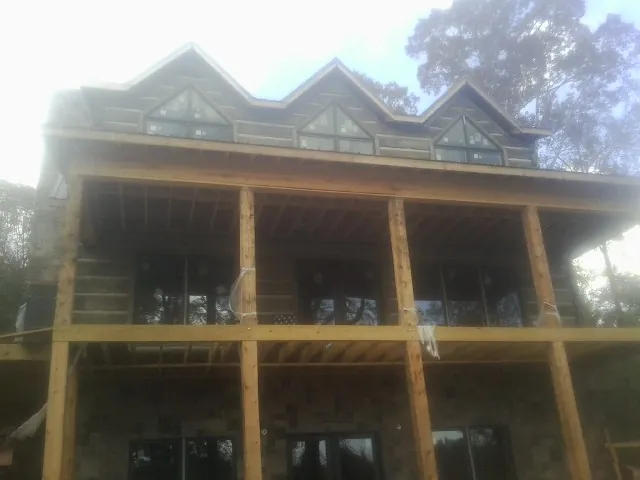 Dormers and porch framing on a large log home under construction — Roof Coating work by our crew in Joliet