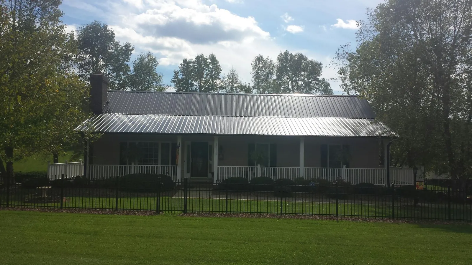 Gray metal roof on a brick ranch with a full width front porch — Gutter Guard Installation work by our crew in Joliet